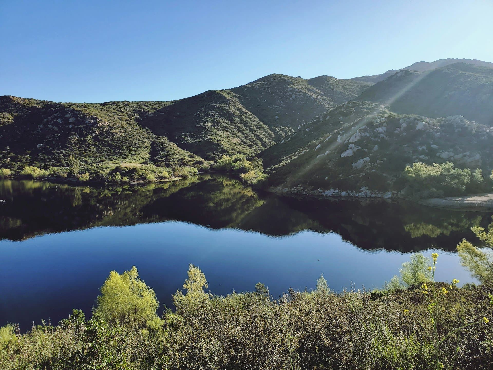 A still reservoir ringed by chaparral hills in San Diego County